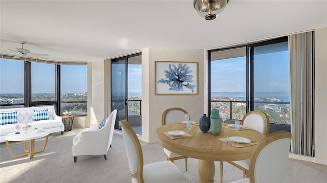 carpeted dining area featuring expansive windows, a water view, and a wealth of natural light