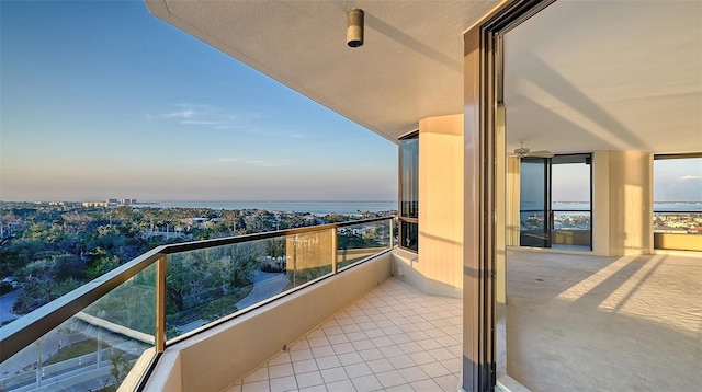 balcony at dusk featuring a water view