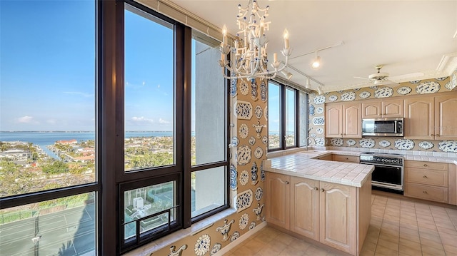 kitchen featuring light brown cabinetry, sink, a water view, tile countertops, and appliances with stainless steel finishes