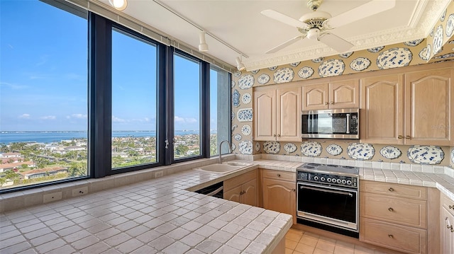 kitchen featuring a water view, sink, tile countertops, and electric range