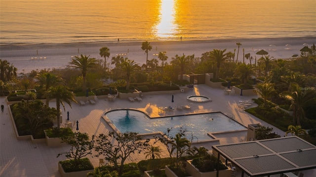 pool at dusk with a water view and a patio