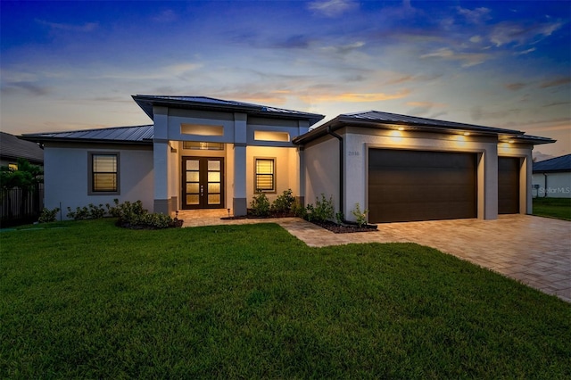 view of front facade with a garage, a lawn, and french doors