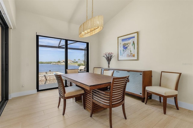 dining space with lofted ceiling, light hardwood / wood-style floors, and a water view