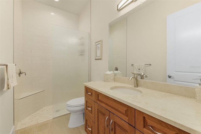 bathroom with vanity, toilet, and a tile shower