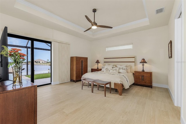 bedroom featuring a water view, ornamental molding, light hardwood / wood-style floors, access to outside, and a raised ceiling