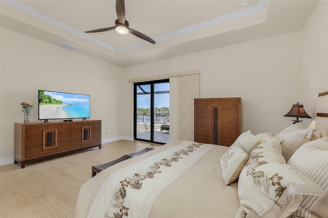 bedroom featuring ceiling fan, access to exterior, a tray ceiling, ornamental molding, and light wood-type flooring