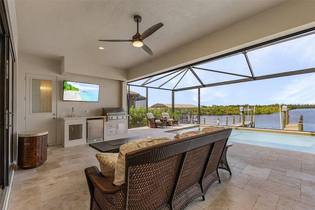 view of patio with a water view, area for grilling, ceiling fan, and sink