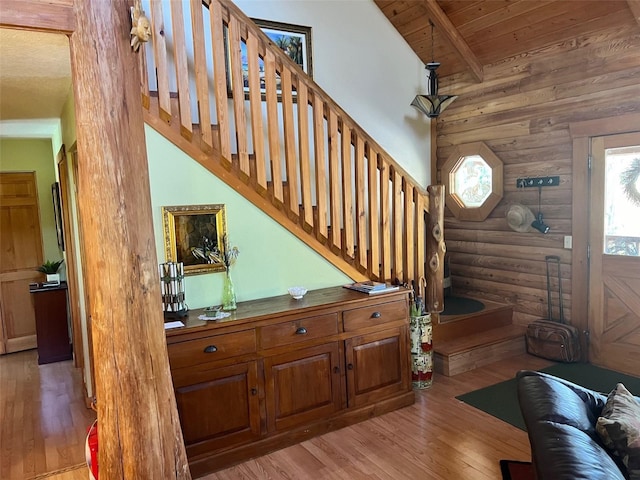 stairs featuring wood-type flooring, vaulted ceiling with beams, rustic walls, and wood ceiling