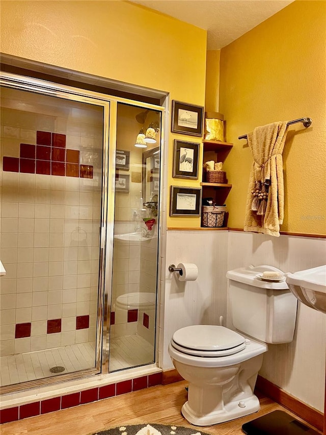 bathroom featuring hardwood / wood-style floors, a shower with door, and toilet