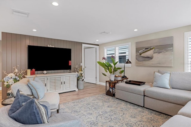 living room with light hardwood / wood-style flooring and wooden walls