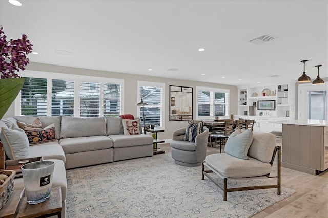 living room with built in features and light wood-type flooring