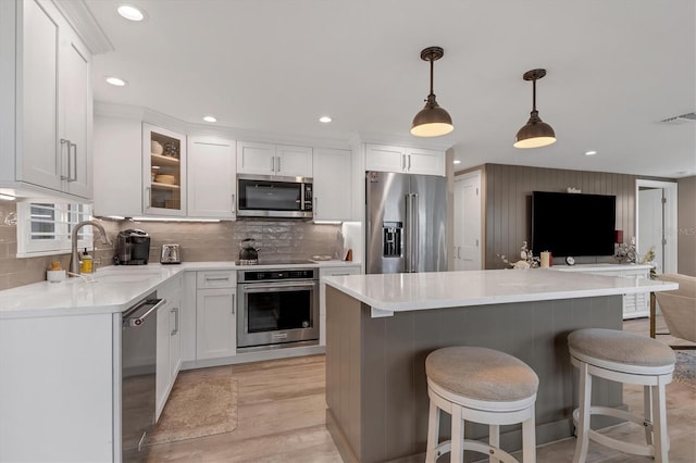 kitchen featuring hanging light fixtures, white cabinetry, appliances with stainless steel finishes, and a kitchen island