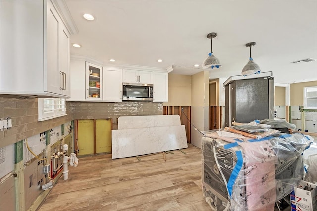 kitchen featuring tasteful backsplash, pendant lighting, white cabinets, and light hardwood / wood-style floors