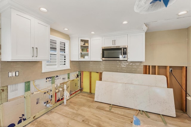 kitchen with white cabinetry, light hardwood / wood-style flooring, and decorative backsplash