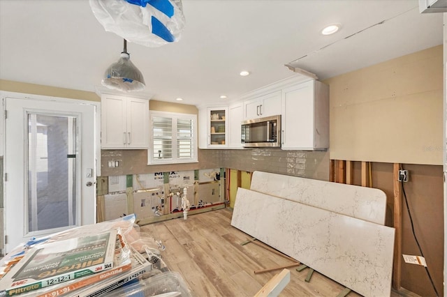 kitchen featuring white cabinetry, backsplash, light hardwood / wood-style floors, and decorative light fixtures