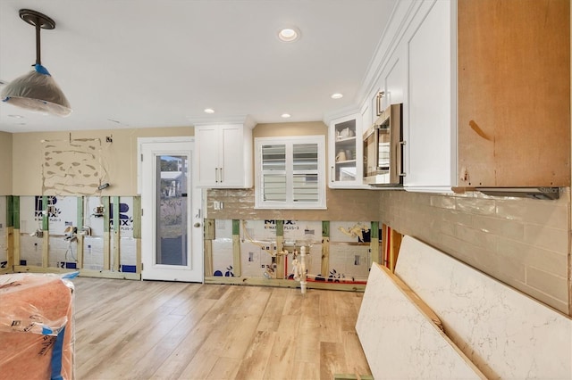 kitchen featuring white cabinetry, hanging light fixtures, backsplash, and light hardwood / wood-style flooring