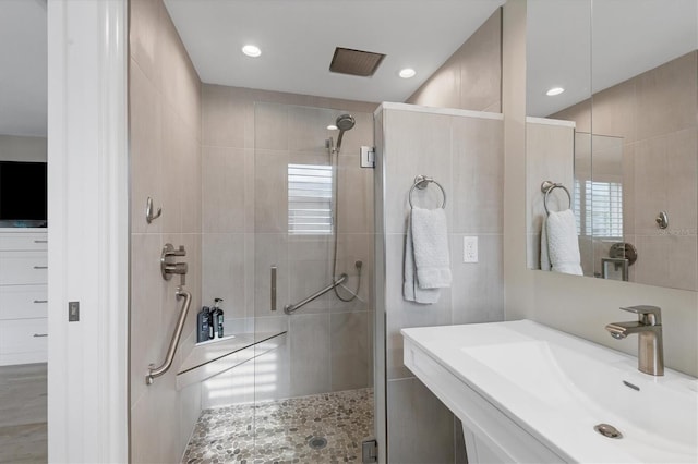 bathroom with a shower with door and sink