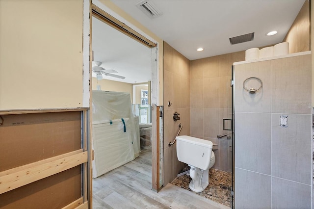 bathroom with tile walls, ceiling fan, hardwood / wood-style flooring, and toilet