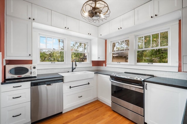 kitchen with sink, white cabinetry, light hardwood / wood-style flooring, appliances with stainless steel finishes, and decorative backsplash