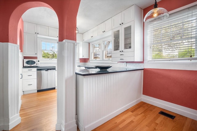 kitchen with decorative light fixtures, white cabinetry, dishwasher, backsplash, and light wood-type flooring