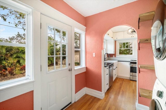 doorway featuring stacked washer and dryer, sink, and light hardwood / wood-style floors