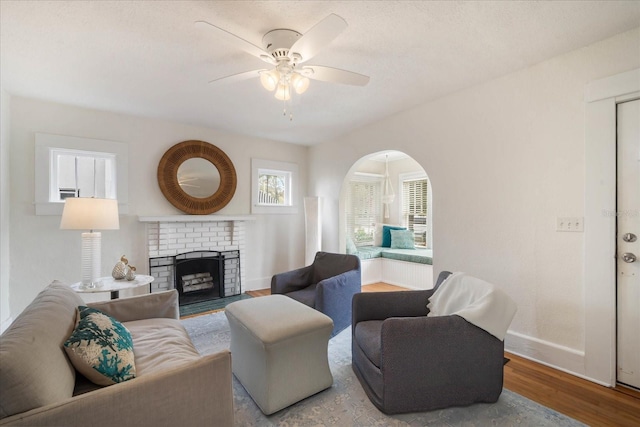 living room featuring ceiling fan, light hardwood / wood-style floors, and a brick fireplace