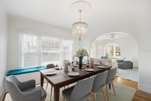 dining area with hardwood / wood-style flooring and ceiling fan with notable chandelier