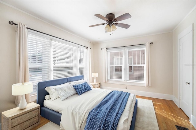 bedroom with multiple windows, crown molding, and light hardwood / wood-style flooring