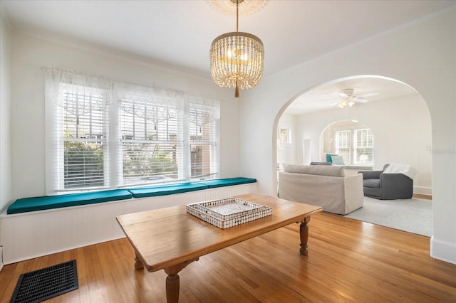 dining area with ceiling fan with notable chandelier and wood-type flooring