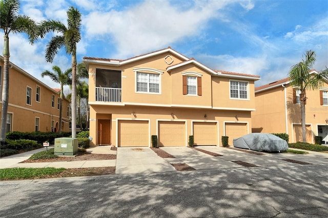 view of property featuring a garage, concrete driveway, and stucco siding