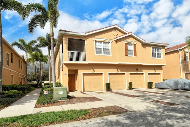 multi unit property featuring driveway, a balcony, a garage, and stucco siding