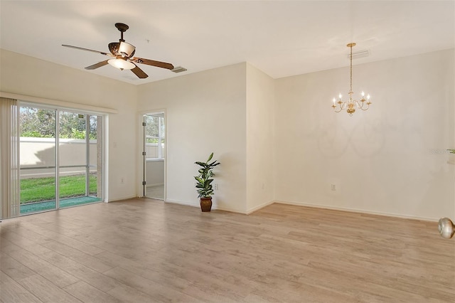 spare room featuring light wood-style floors, visible vents, baseboards, and ceiling fan with notable chandelier