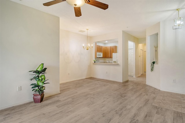 unfurnished living room featuring ceiling fan with notable chandelier, visible vents, light wood-style flooring, and baseboards