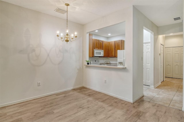 kitchen featuring light wood finished floors, white appliances, brown cabinetry, and visible vents