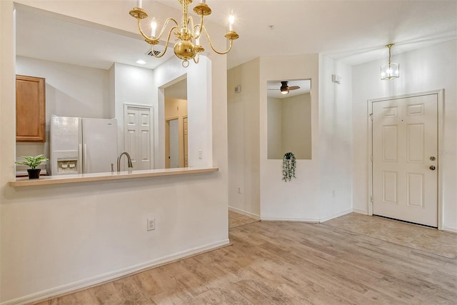 interior space featuring ceiling fan with notable chandelier, a sink, wood finished floors, and baseboards