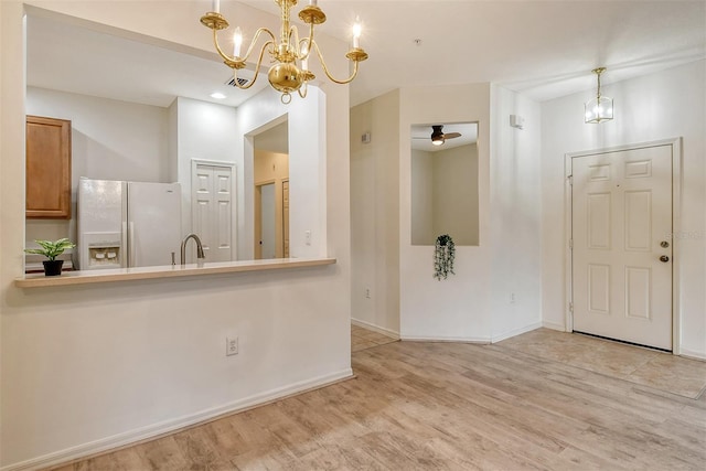 interior space featuring ceiling fan with notable chandelier, wood finished floors, and baseboards