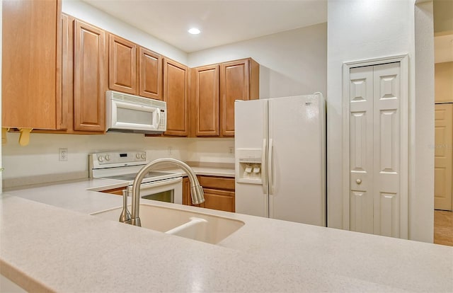 kitchen featuring light countertops, white appliances, a sink, and recessed lighting