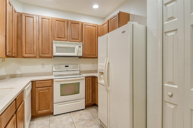 kitchen with recessed lighting, light countertops, brown cabinetry, light tile patterned flooring, and white appliances