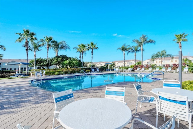 pool with outdoor dining area and a residential view