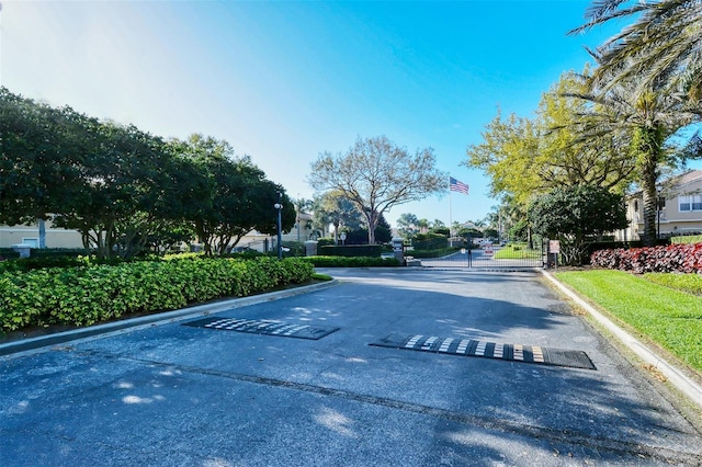 view of street featuring a gated entry and curbs