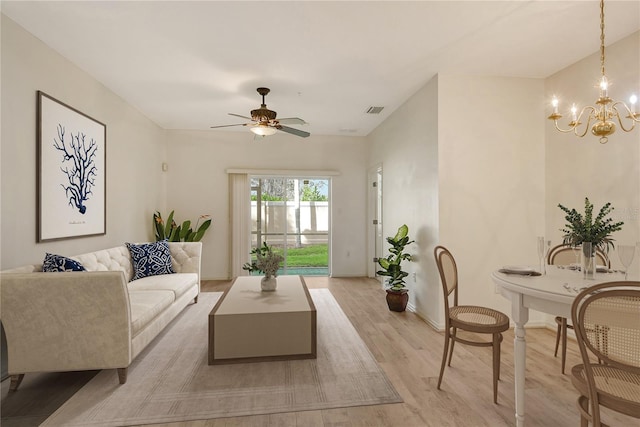 living area featuring light wood-style floors, visible vents, baseboards, and ceiling fan with notable chandelier