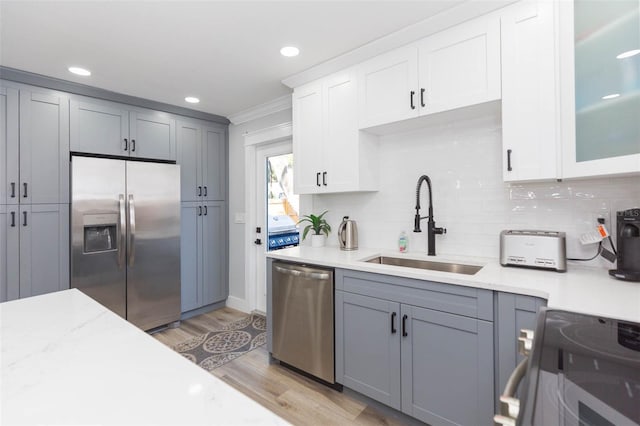 kitchen with sink, white cabinets, backsplash, stainless steel appliances, and light hardwood / wood-style flooring