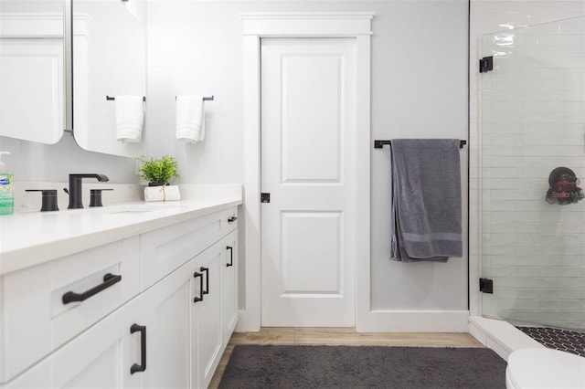 bathroom with vanity, toilet, and a shower with door