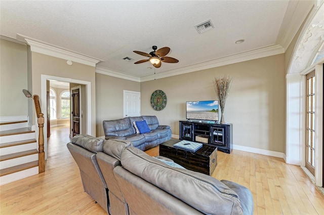 living room with ceiling fan, ornamental molding, light hardwood / wood-style flooring, and a textured ceiling