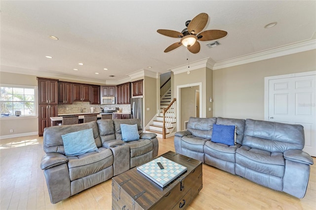 living room with ornamental molding, ceiling fan, and light wood-type flooring