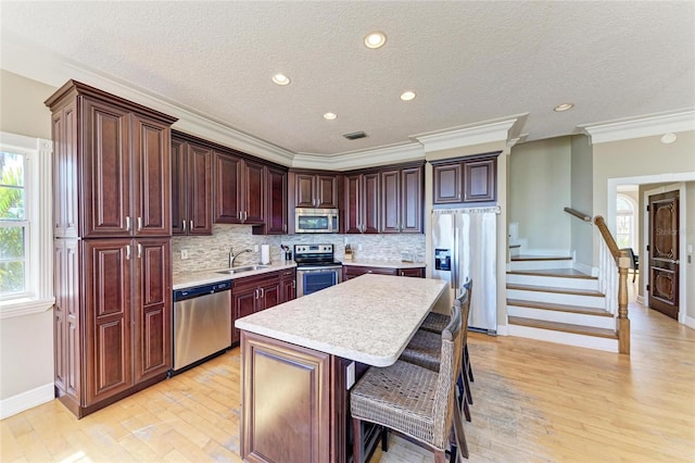 kitchen featuring sink, a breakfast bar area, backsplash, stainless steel appliances, and a center island