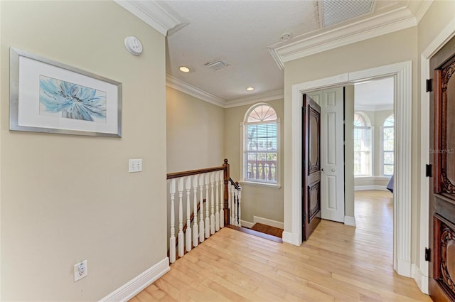 hallway with a wealth of natural light, light hardwood / wood-style flooring, and ornamental molding