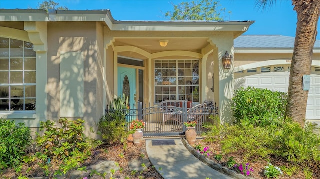 view of exterior entry with stucco siding and an attached garage