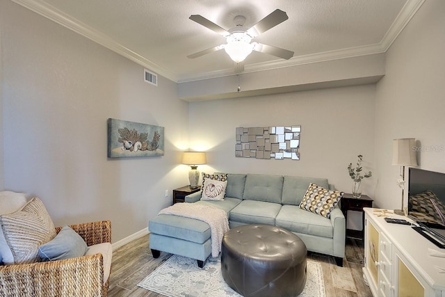 living room with ceiling fan, ornamental molding, a textured ceiling, and light wood-type flooring