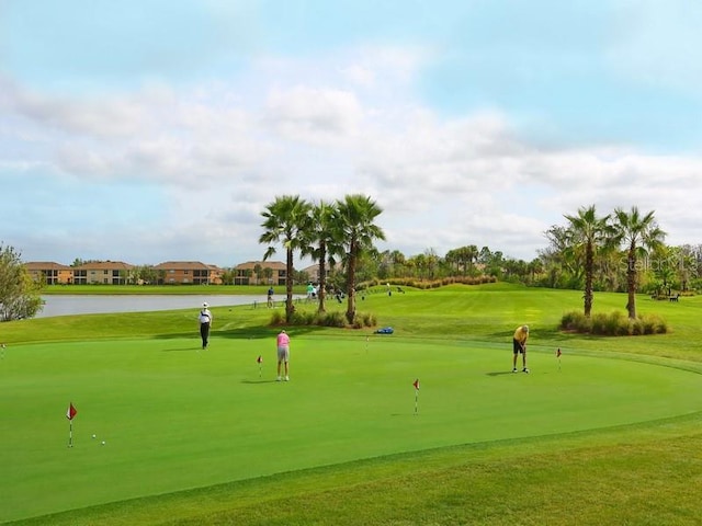 surrounding community with a water view and a lawn